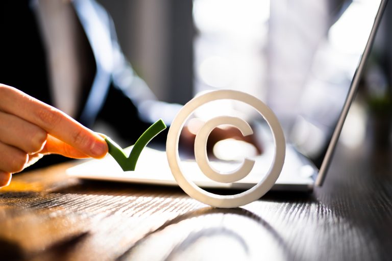 Vor einem offenen Laptop steht ein Copyright-Logo.
