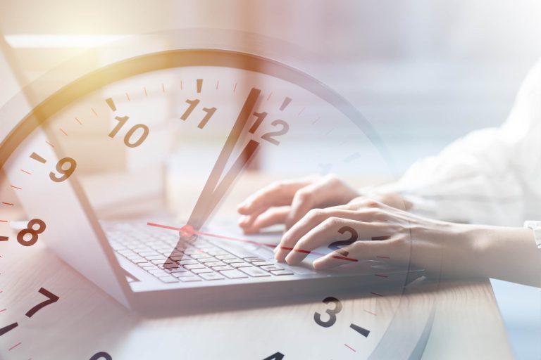 Mann tippt auf Computer, im Hintergrund schimmert eine Uhr