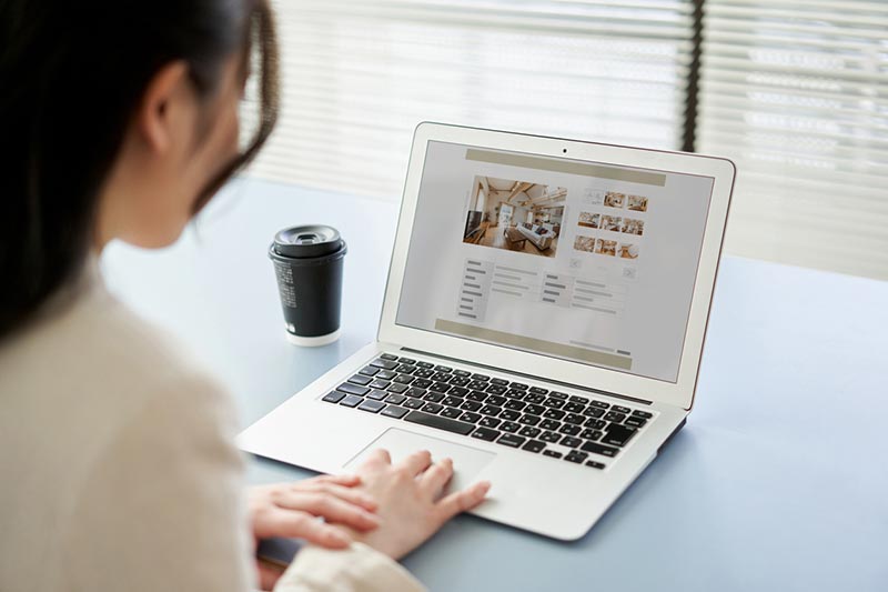 Frau sitzt am Laptop und schaut sich eine Website an.